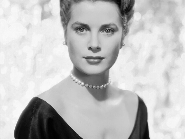 Black-and-white studio portrait of Grace Kelly in a dark evening dress and pearl necklace.