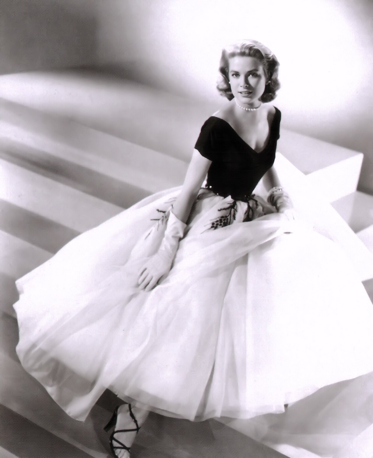 Grace Kelly sits in an elegant black-and-white evening gown in a publicity portrait for Rear Window.