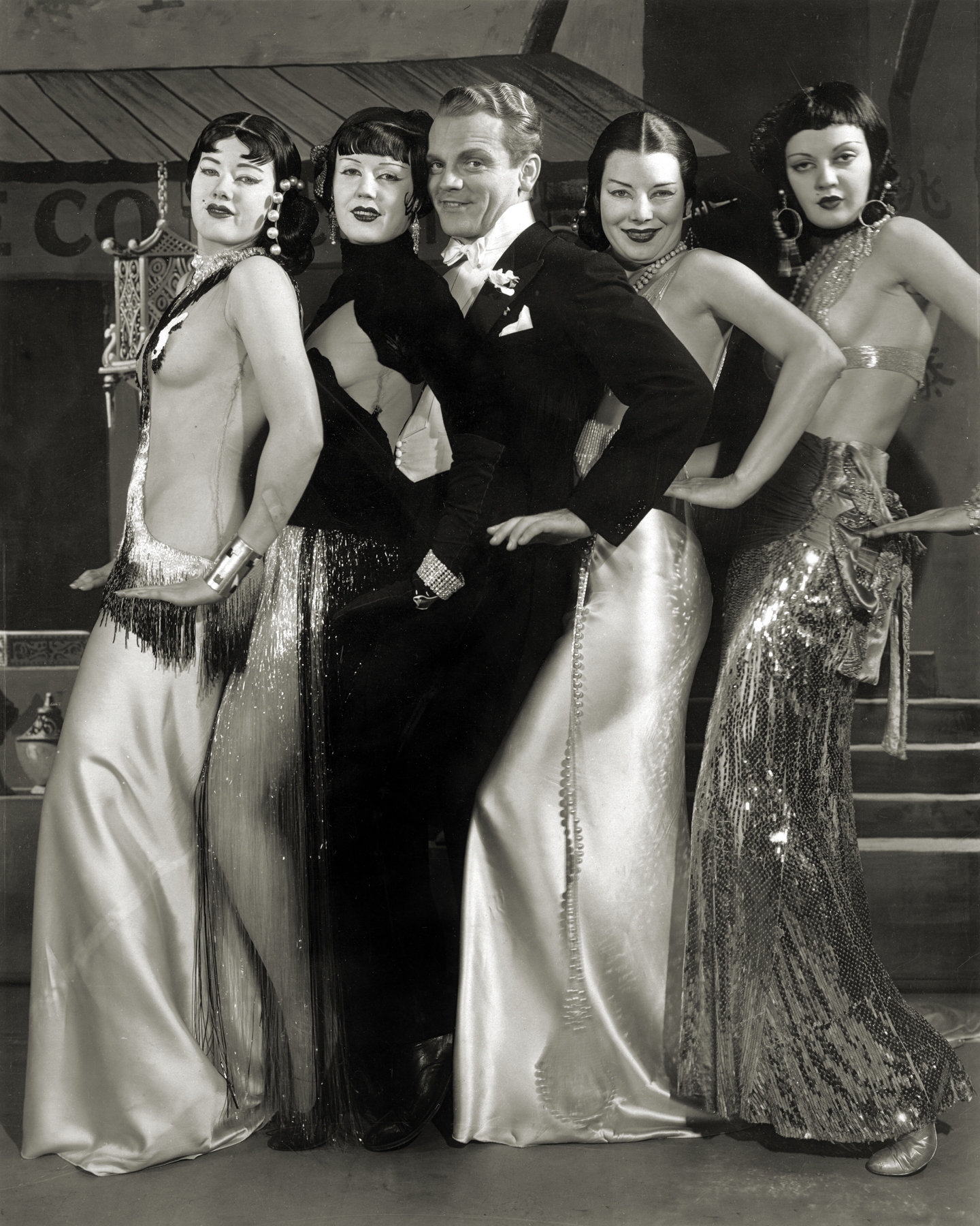 James Cagney in a tuxedo surrounded by four women in costumes for the Shanghai Lil number in Footlight Parade.