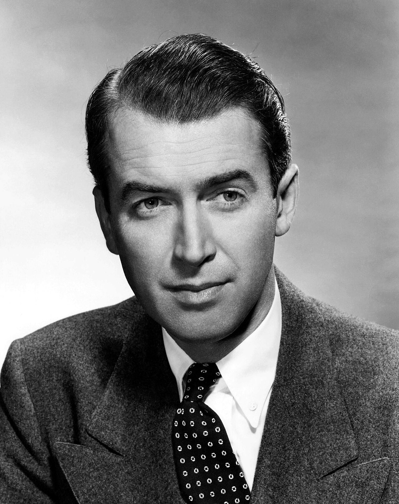 Black-and-white head-and-shoulders studio portrait of James Stewart in a suit and patterned tie.
