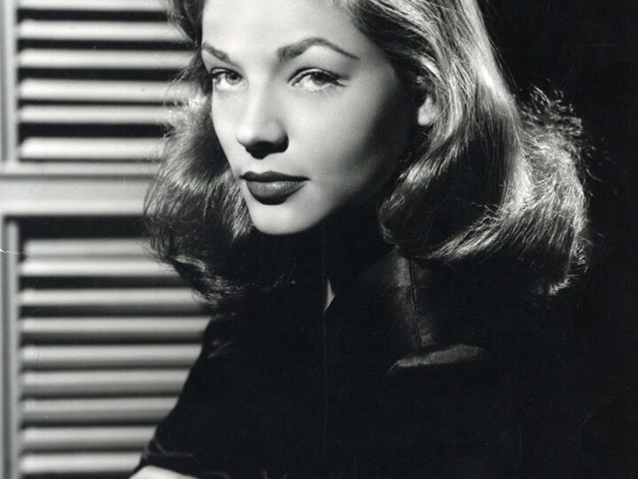 Black-and-white 1945 press portrait of Lauren Bacall looking toward the camera with her chin lowered.