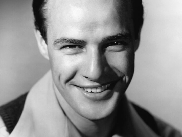 Black-and-white early-career studio portrait of a smiling Marlon Brando for The Men.