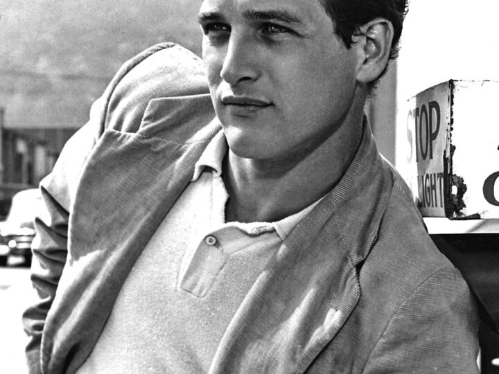Black-and-white early-career portrait of Paul Newman seated outdoors in a light shirt and jacket.