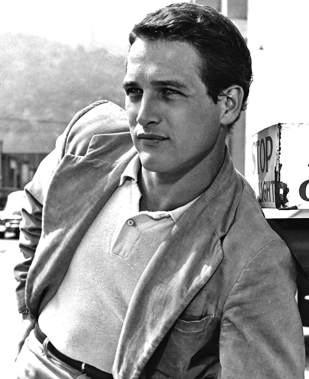 Black-and-white early-career portrait of Paul Newman seated outdoors in a light shirt and jacket.