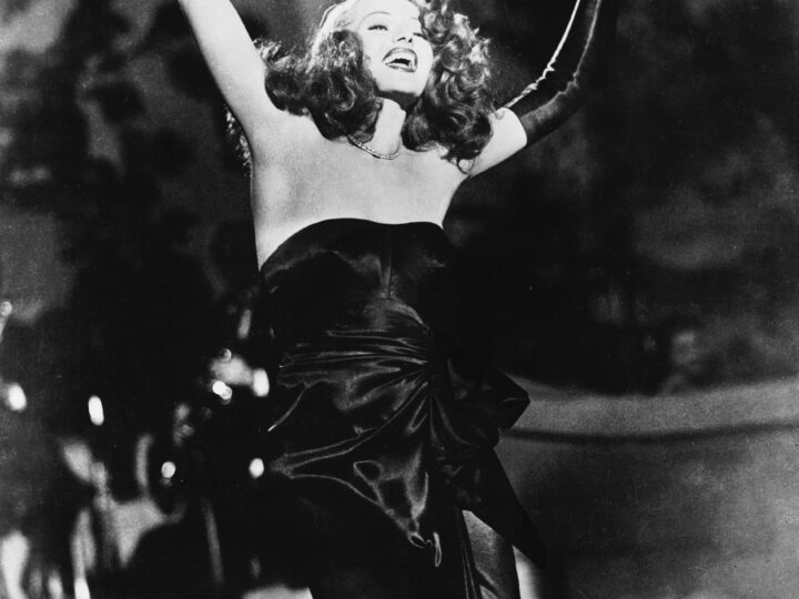 Rita Hayworth performing in a strapless black dress and long gloves in a publicity image for Gilda.