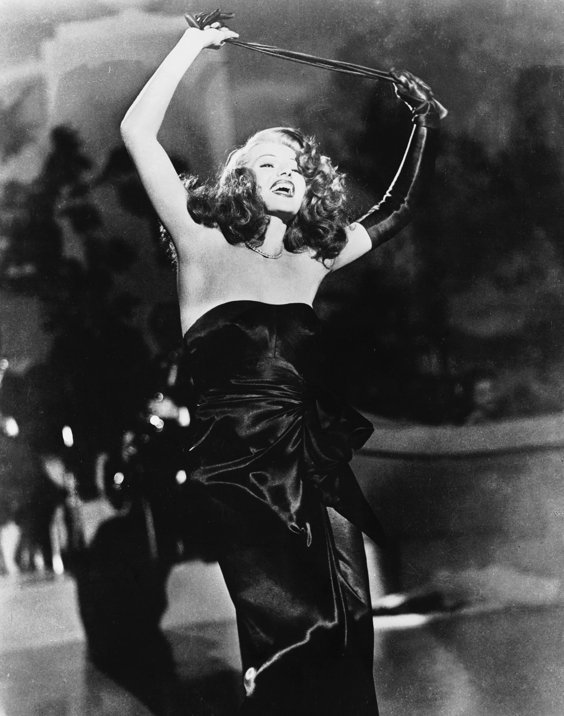 Rita Hayworth performing in a strapless black dress and long gloves in a publicity image for Gilda.