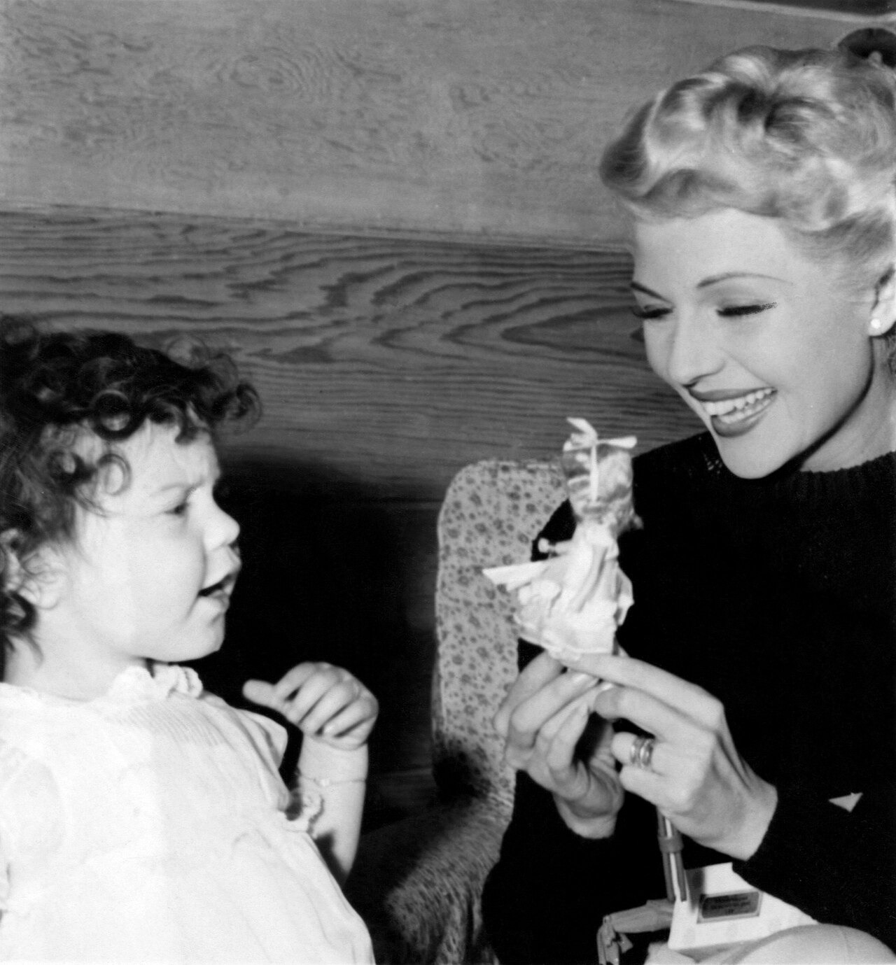 Rita Hayworth seated with her two-year-old daughter Rebecca Welles while showing her a toy in 1946.