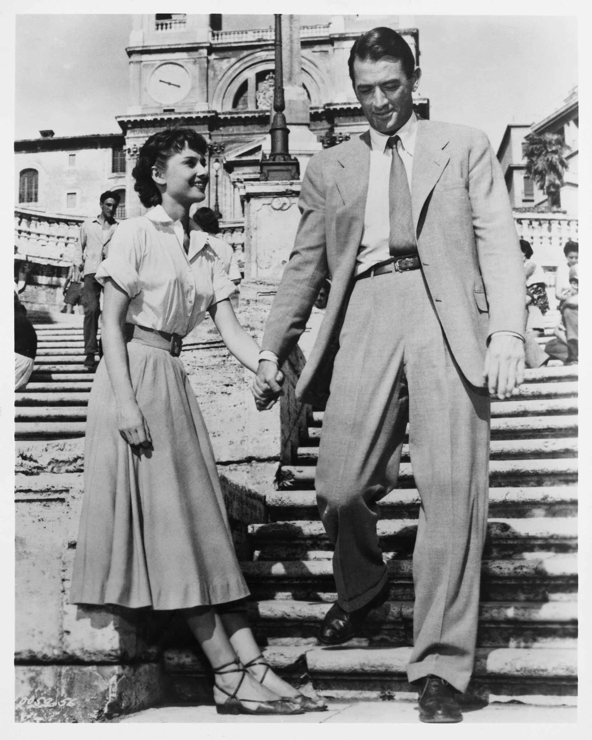 Audrey Hepburn and Gregory Peck smiling together in a Roman Holiday publicity portrait.