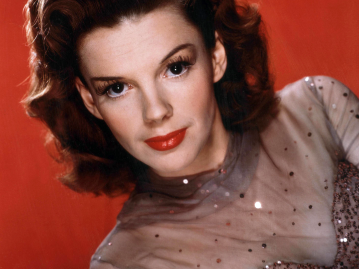 Color publicity portrait of Judy Garland against a red background in the mid-1940s.
