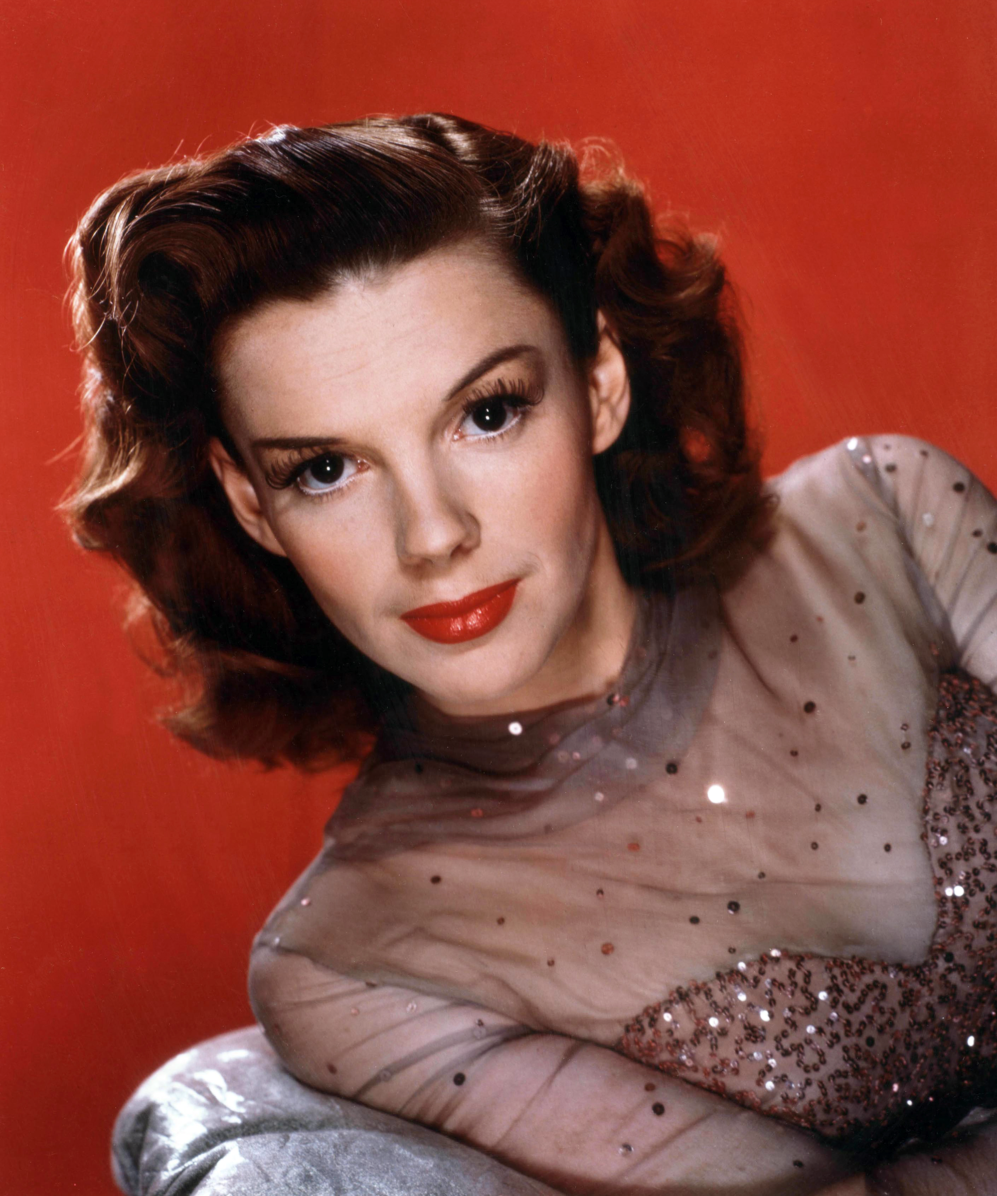 Color publicity portrait of Judy Garland against a red background in the mid-1940s.