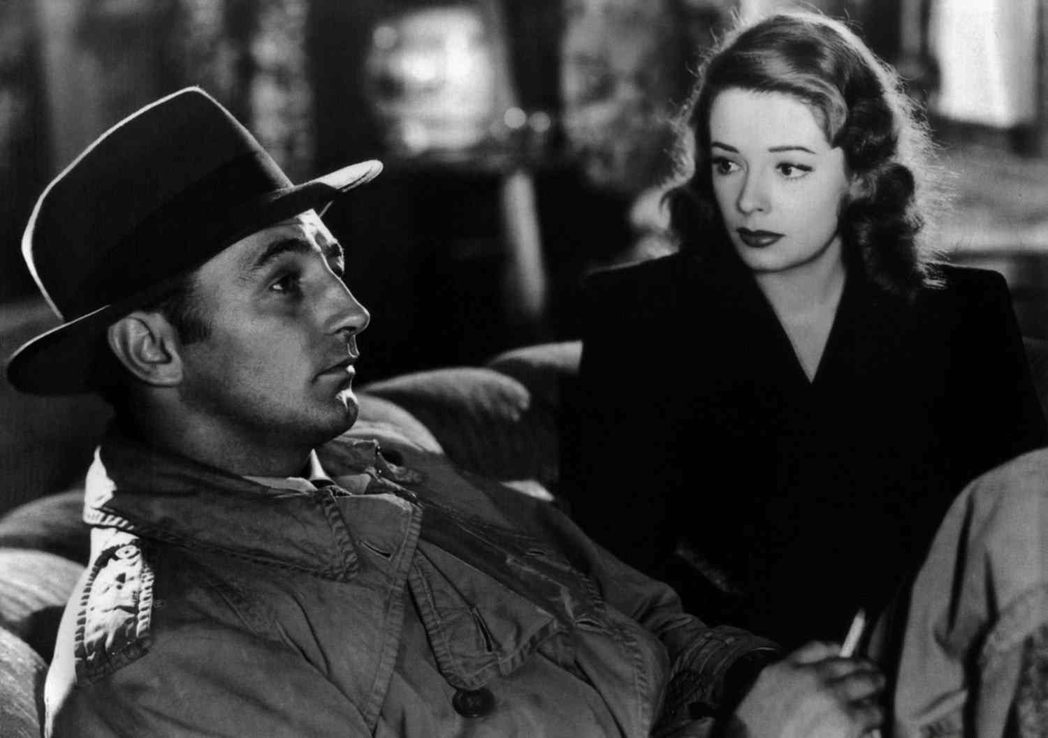 Black-and-white publicity photograph of Robert Mitchum in a trench coat beside Jane Greer in Out of the Past.