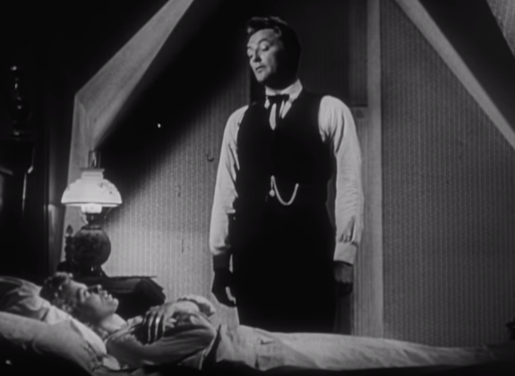 Black-and-white trailer image of Robert Mitchum as Harry Powell leaning over Shelley Winters in The Night of the Hunter.